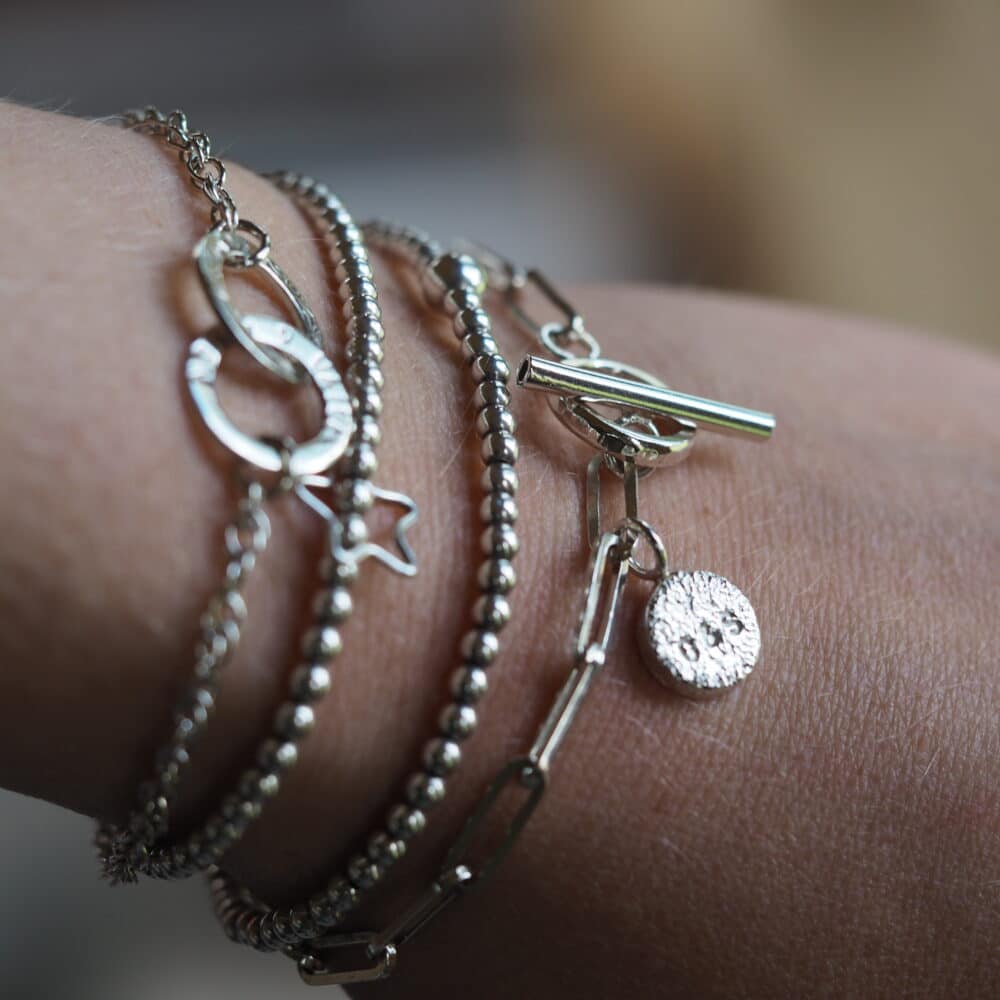stacked silver bangles and bracelets on wrist