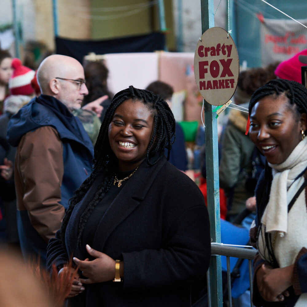 smiling traders at busy Crafty Fox Market at Kings Cross