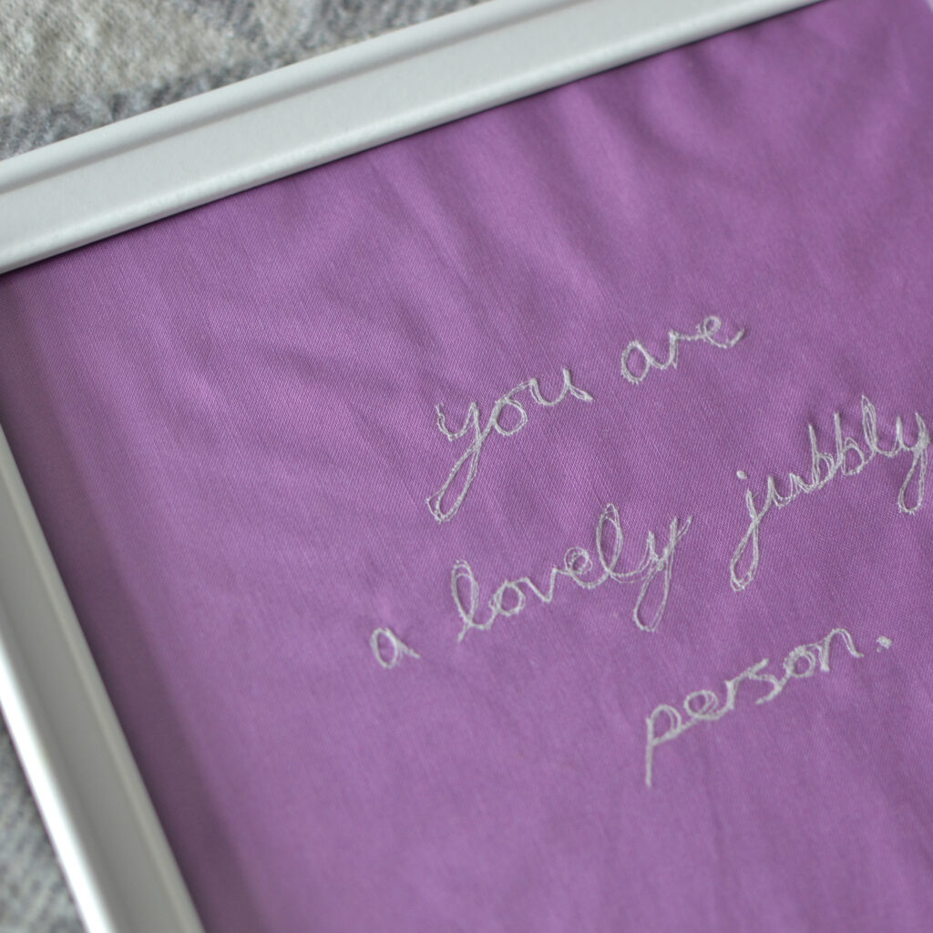 framed bright purple textile artwork by loaf & bear - embroidered text says 'you are a lovely jubbly person'