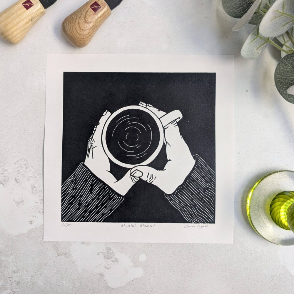 Carrie Lyall Printmaker, a linocut of two hands holding a coffee cup