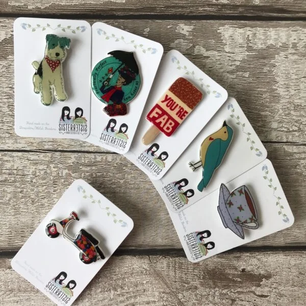 Photograph Of Hand Painted Ceramic Heart Featuring A Black Labrador Wearing A Red And Green Stripey Scarf Sitting Down In The Snow with Raised Elements To Represent Snow