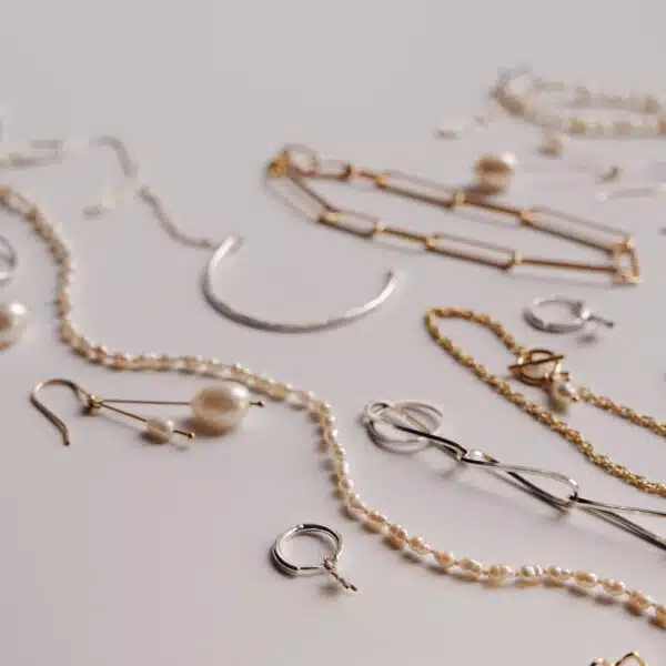 Flat lay of KiJo Jewellery crescent moon necklaces, pearls, earrings, and chain bracelets on light grey background