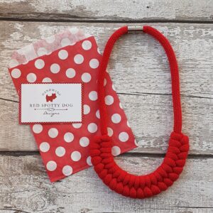 red Jayne style knotted necklace lay onto of red spotty paper bag abd business card