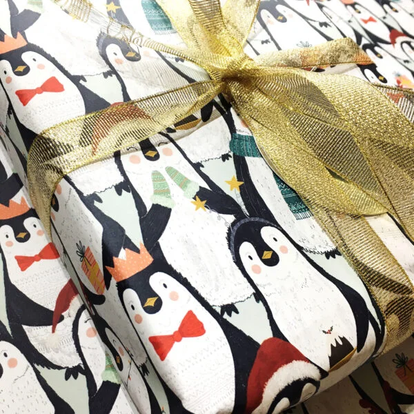 Recyclable Christmas Penguin Gift Wrap shown with gold ribbon by Ellie Cartlidge Design