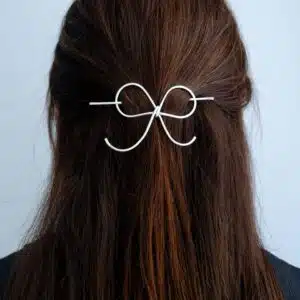 Handmade silver bow hair pin worn in half-up, half-down hairstyle – minimal hair accessory.