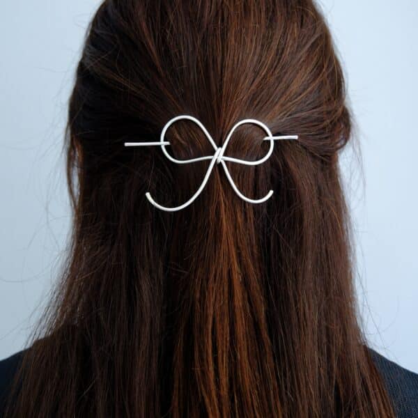 Handmade silver bow hair pin worn in half-up, half-down hairstyle – minimal hair accessory.