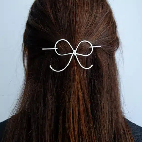 Handmade silver bow hair pin worn in half-up, half-down hairstyle – minimal hair accessory.