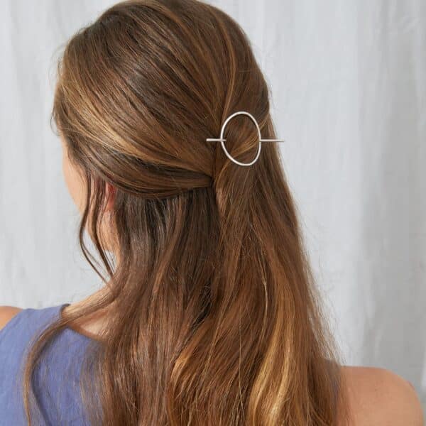 Siver circle hair pin by KiJo Jewellery styled in half-up hairstyle on model with long blonde hair and dusty blue top.