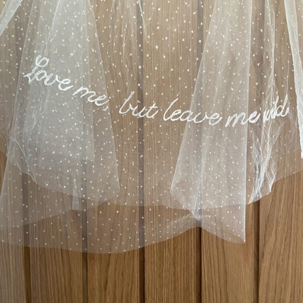 A wedding veil featuring delicate embroidered lettering with a personalised phrase stitched into the fabric.