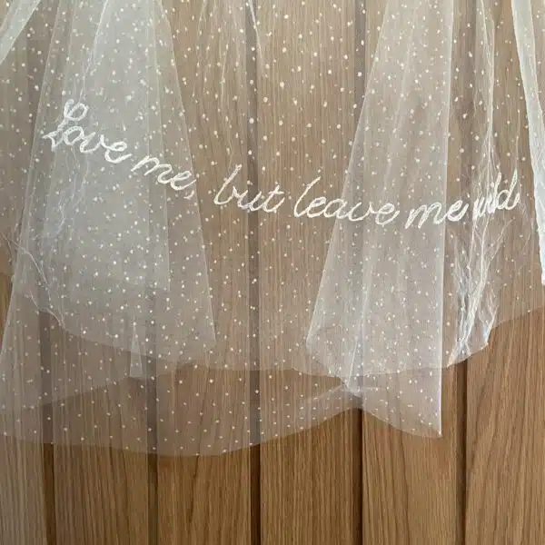 A wedding veil featuring delicate embroidered lettering with a personalised phrase stitched into the fabric.