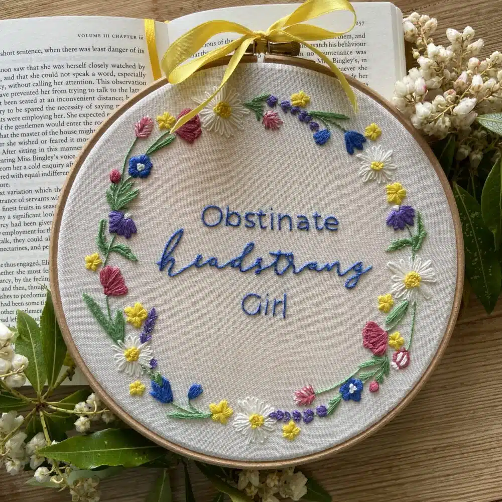 An embroidery kit featuring the quote “Obstinate, Headstrong Girl” in an elegant embroidered design, complete with embroidery supplies and instructions.