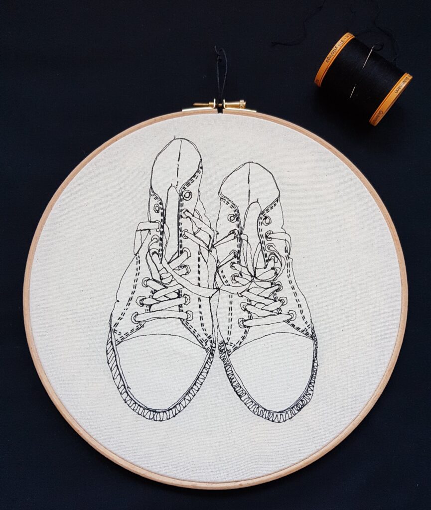 Gemma Rappensberger Converse trainers illustration using free motion machine embroidery in black thread with black hand embroidery thread details, displayed in a 10" wooden embroidery hoop.