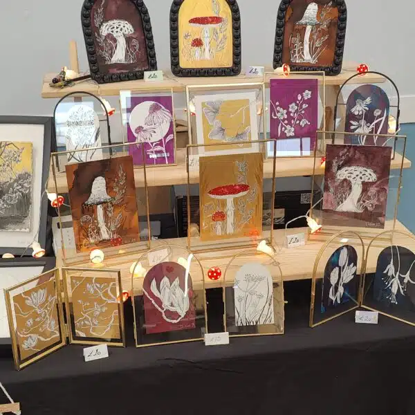 Art stall displaying framed artwork with a mix of mushrooms and flowers