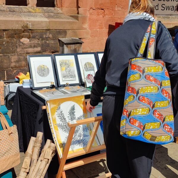 Art stall displaying framed artwork with a visitor at the front