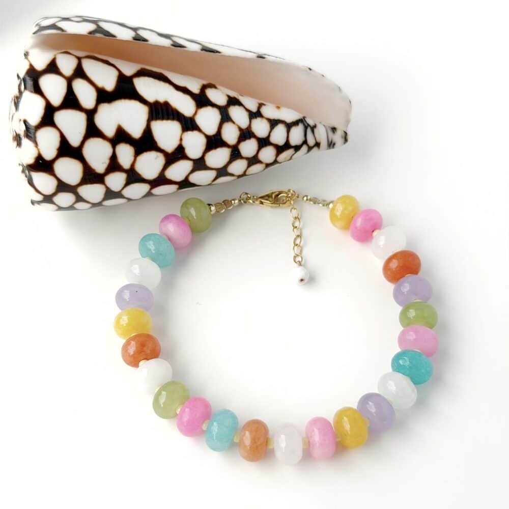 multicoloured jasper gemstone bracelet with gold filled clasp and extension chain displayed against a white background next to a sea shell