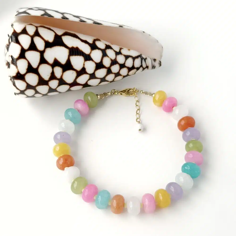 multicoloured jasper gemstone bracelet with gold filled clasp and extension chain displayed against a white background next to a sea shell