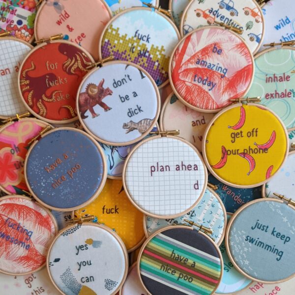 Little light stitchery pile of quote hoops. Lots of different hand embroidered quote hoops on colourful and patterned fabric
