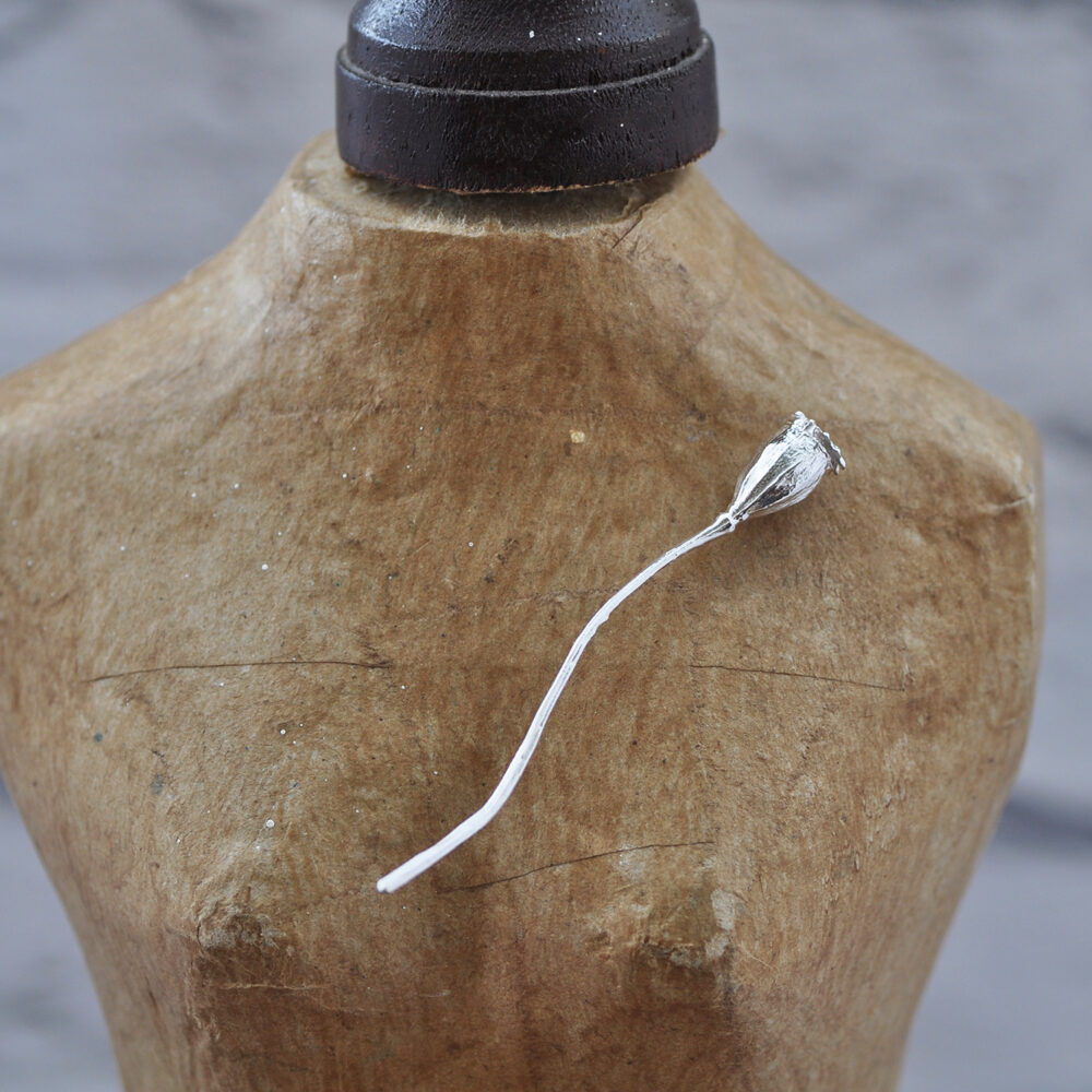 Upside Down Tree Studio, Poppy seed head lapel pin pinned to the bust of a vintage mannequin