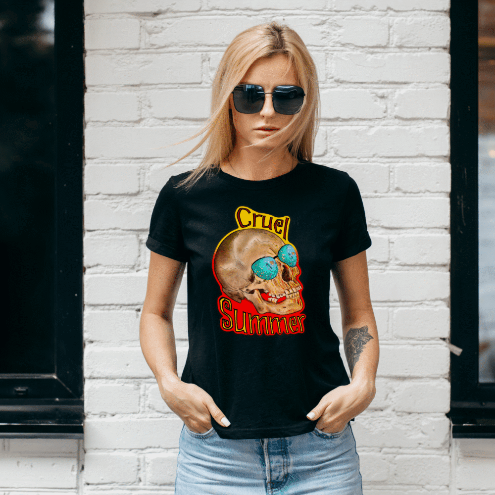 A blonde woman models a black T-shirt with the "Cruel Summer" design on the front. This design is a skull wearing mirror sunglasses, with a hot orange outline.
