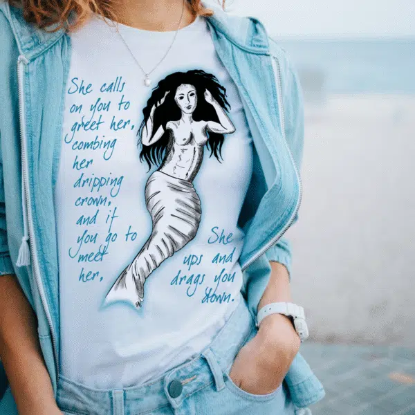 Woman wearing a white T-shirt featuring a drawing of a mermaid and a poem about mermaids.