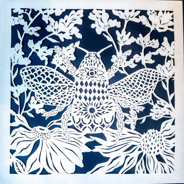 Mushypeadesign Summer Bee - Hand cut paper art with image of a bee and bee friendly flowers, white on a midnight blue background with ice white card mount