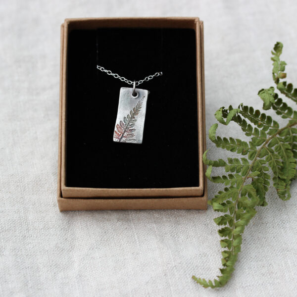 small rectangular silver pendant with fern leaf print