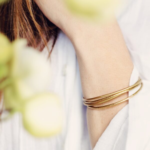 KiJo Jewellery: Thin Gold bangle stacking set worn as a stack with white blouse and foreground flowers