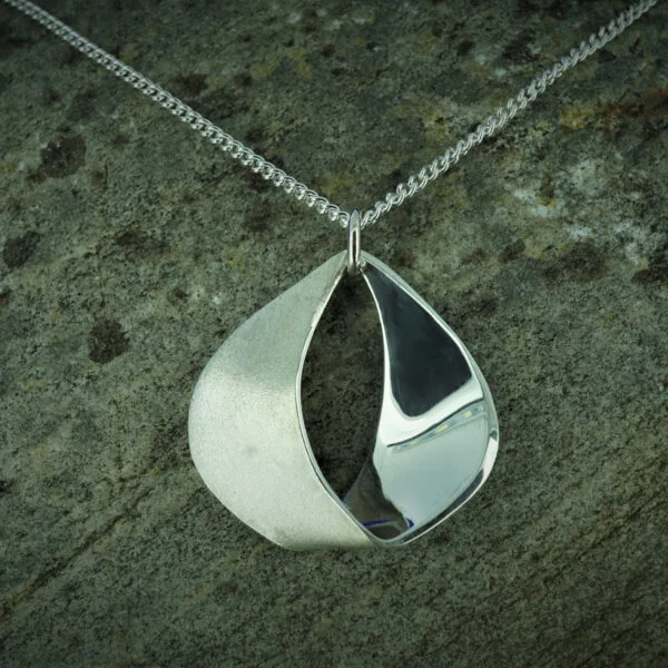 The Silevr Bird tear drop pendant with contrasting polished and frosted finish, on chain with stone background