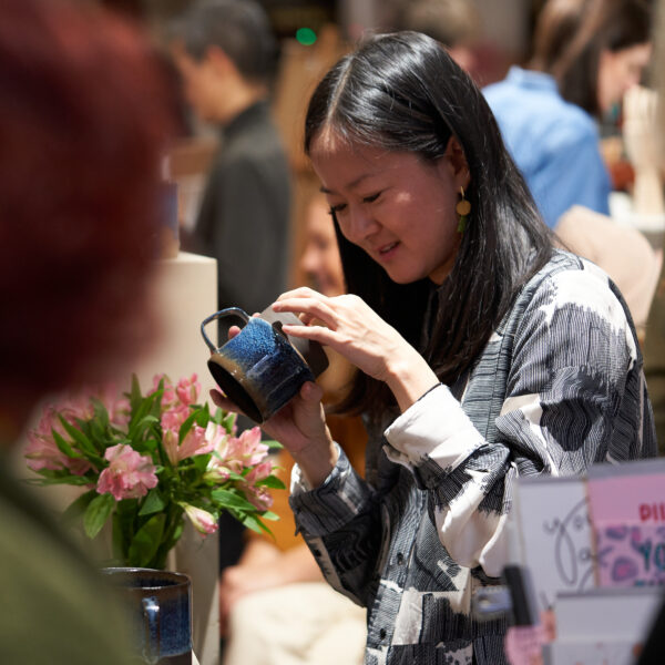 Shopper inspecting a handmade mug at Crafty Fox Market