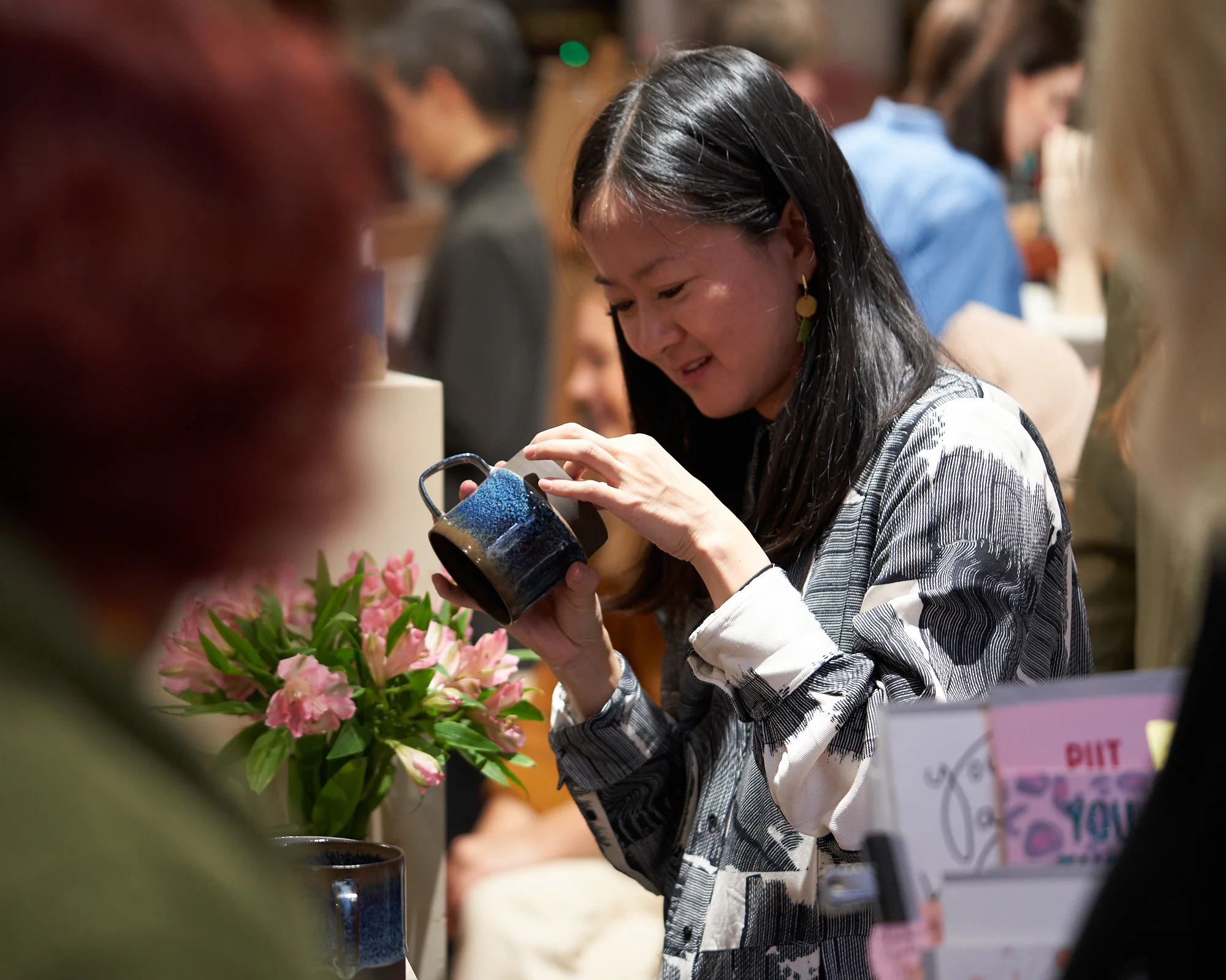 Shopper inspecting a handmade mug at Crafty Fox Market