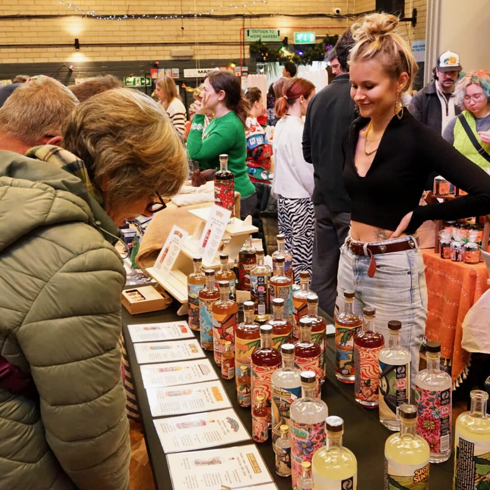 Shoppers browsing a colourful independent drinks stall at the Brighton Festive Makers Fair at Wagner Hall.
