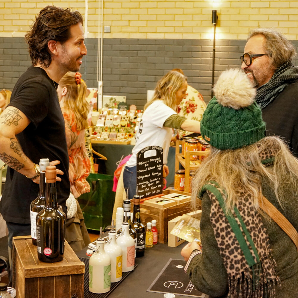 Shoppers chatting with an independent maker at a festive stall inside the Brighton Makers Fair at Wagner Hall.
