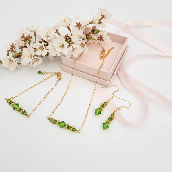 Watermeadow Lane Jewellery three pieces of jewellery consisting of necklace, bracelet and drop earrings, all in gold beads and green crystals to create a bar necklace and bracelet and straight drop earrings.