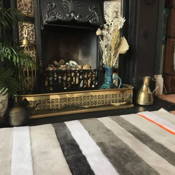 A view of a striped sheepskin rug in front of a fireplace.
