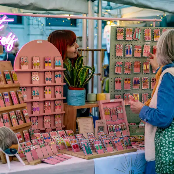 Female street market trader taking payment from a customer selling bright polymer jewellery