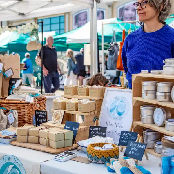 Female market trader standing behind a market stall selling handmade soaps and body care