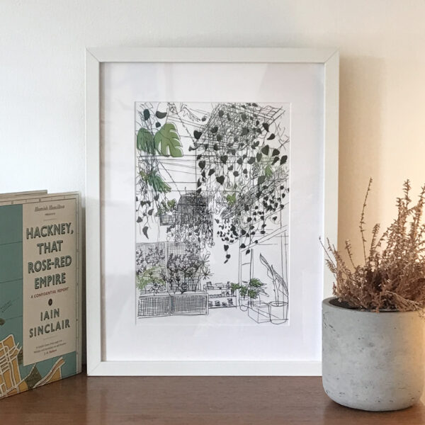 Framed illustration on wooden surface with book and plant
