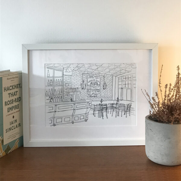 Framed illustration of inside a pub, on wooden surface with plant and book