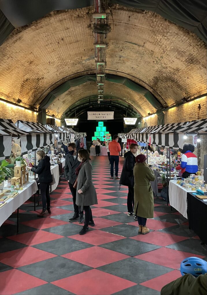 There are stalls set up in a tunnel space for a craft market.