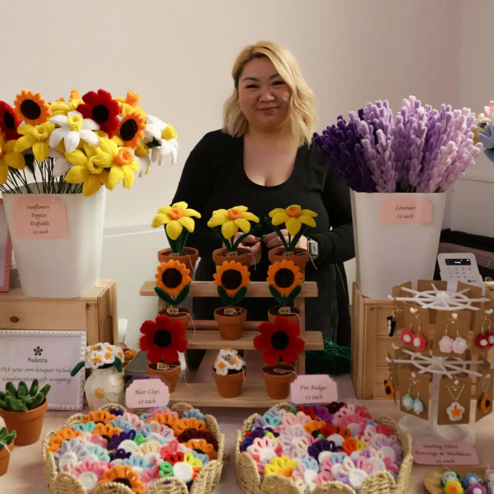 Smiling stallholder in front of their stall of flowers