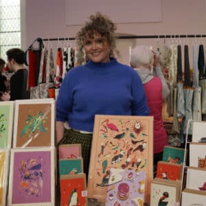Smiling stallholder in front of their stall of artwork