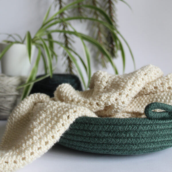 A shallow green rope bowl with a cream knitting project