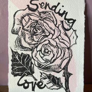 Mandy Benton Printmaker, 'Sending Love' Linocut Print. A small linocut print on a beautiful handmade paper depicting roses and the message 'Sending Love'. Printed in black ink over a sweep of pink watercolour paint.