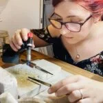 Jen Lithgo woldering a pair of stud earrings in her home studio