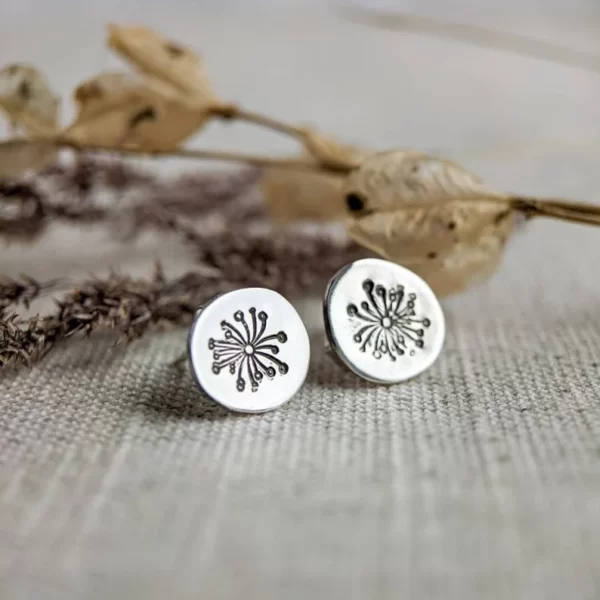 A pair of silver round stud earrings, stamped with a dandelion motif