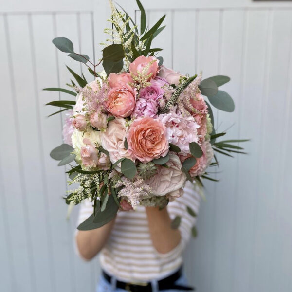 Lady holding a large bouquet of pink flowers in front of her face