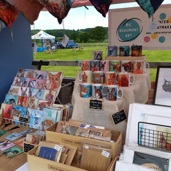 Close up shot of a stall in Worcestershire, featuring mugs, greeting cards, lino prints, coasters - lots of colour, lots of animals and nature inspired work