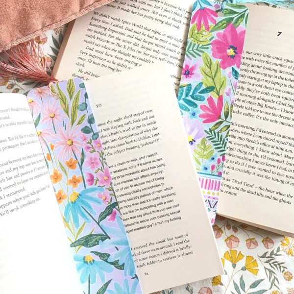 Two watercolour floral bookmarks from Ellie Cartlidge Design shown saving the pages in two books