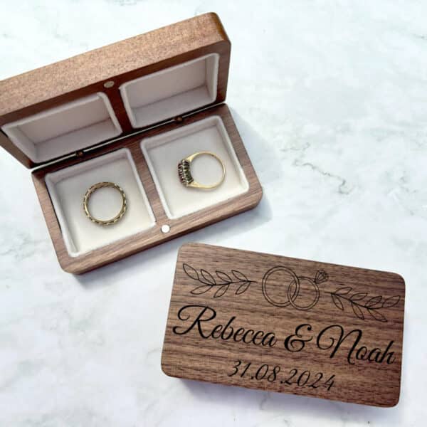 Laser-engraved walnut ring box featuring a personalised couple's name and date, with a wedding ring design.