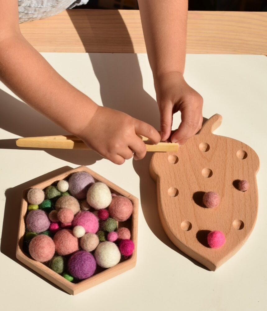 Little Ones, acorn fine motor board being used with felt balls